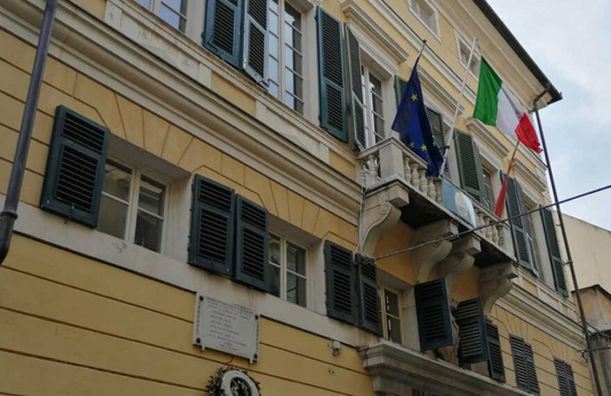 Facciata del municipio di Finale Ligure con bandiere istituzionali su balcone