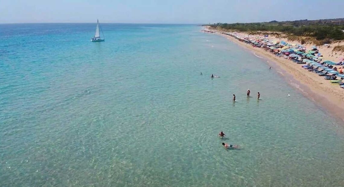 Veduta aerea della spiaggia libera di Pescoluse affollata di bagnanti e ombrelloni