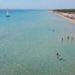 Veduta aerea della spiaggia libera di Pescoluse affollata di bagnanti e ombrelloni