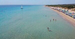 Veduta aerea della spiaggia libera di Pescoluse affollata di bagnanti e ombrelloni