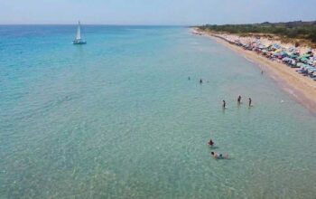 Veduta aerea della spiaggia libera di Pescoluse affollata di bagnanti e ombrelloni