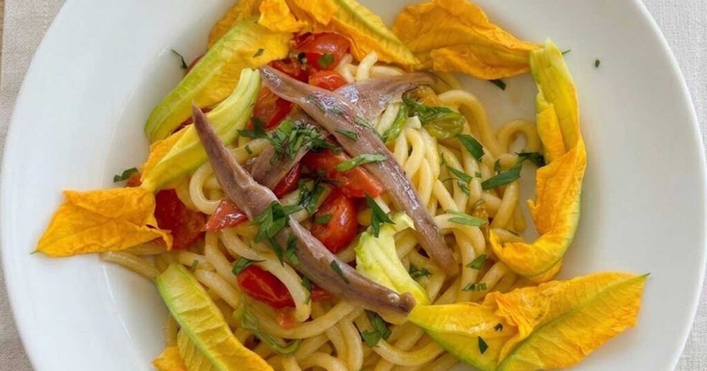 Piatto di pasta con fiori di zucca e alici fresche della tradizione culinaria di Sperlonga
