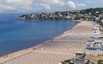 Vista panoramica dall'alto della spiaggia di Serapo a Gaeta con stabilimenti balneari e ombrelloni disposti lungo la costa