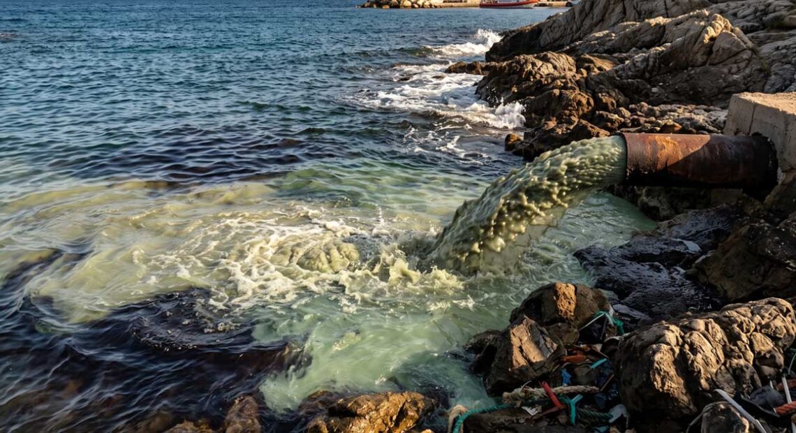 Sversamento di acque reflue e inquinanti in mare da un tubo sulla costa.