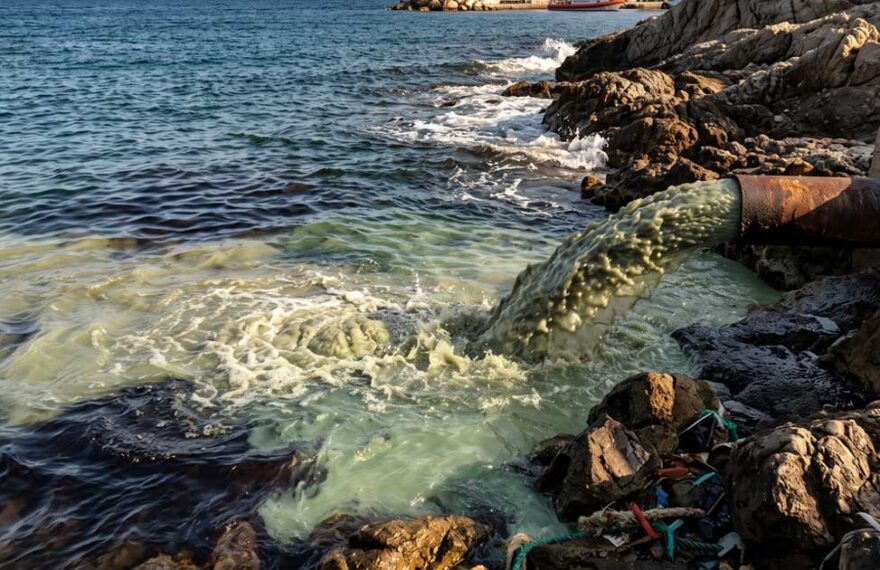 Sversamento di acque reflue e inquinanti in mare da un tubo sulla costa.