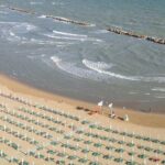 Veduta aerea della spiaggia di Termoli a settembre con lettini ordinati e bagnanti in mare.