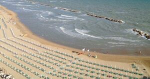 Veduta aerea della spiaggia di Termoli a settembre con lettini ordinati e bagnanti in mare.