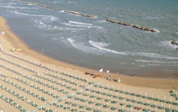 Veduta aerea della spiaggia di Termoli a settembre con lettini ordinati e bagnanti in mare.