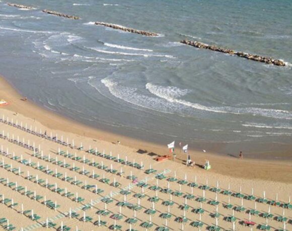 Veduta aerea della spiaggia di Termoli a settembre con lettini ordinati e bagnanti in mare.