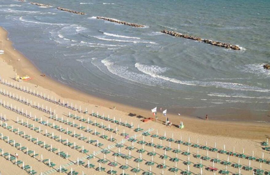 Veduta aerea della spiaggia di Termoli a settembre con lettini ordinati e bagnanti in mare.