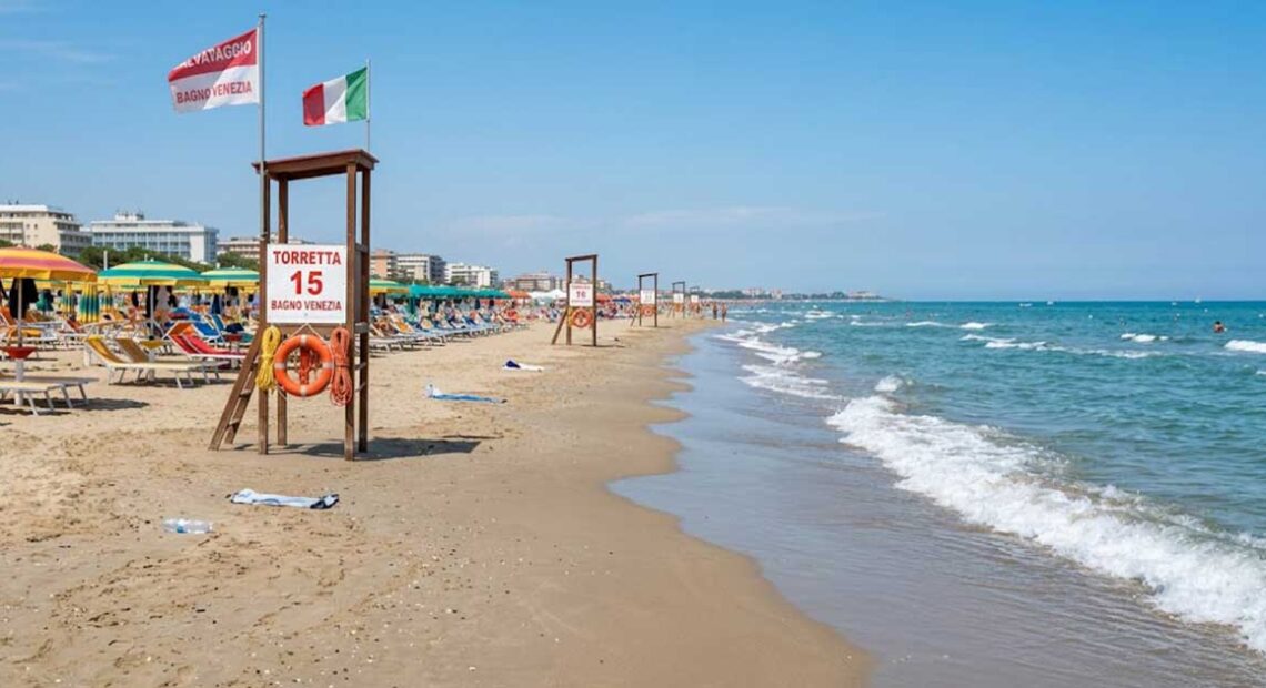 Torretta di salvataggio vuota sulla spiaggia con ombrelloni e mare calmo sullo sfondo.