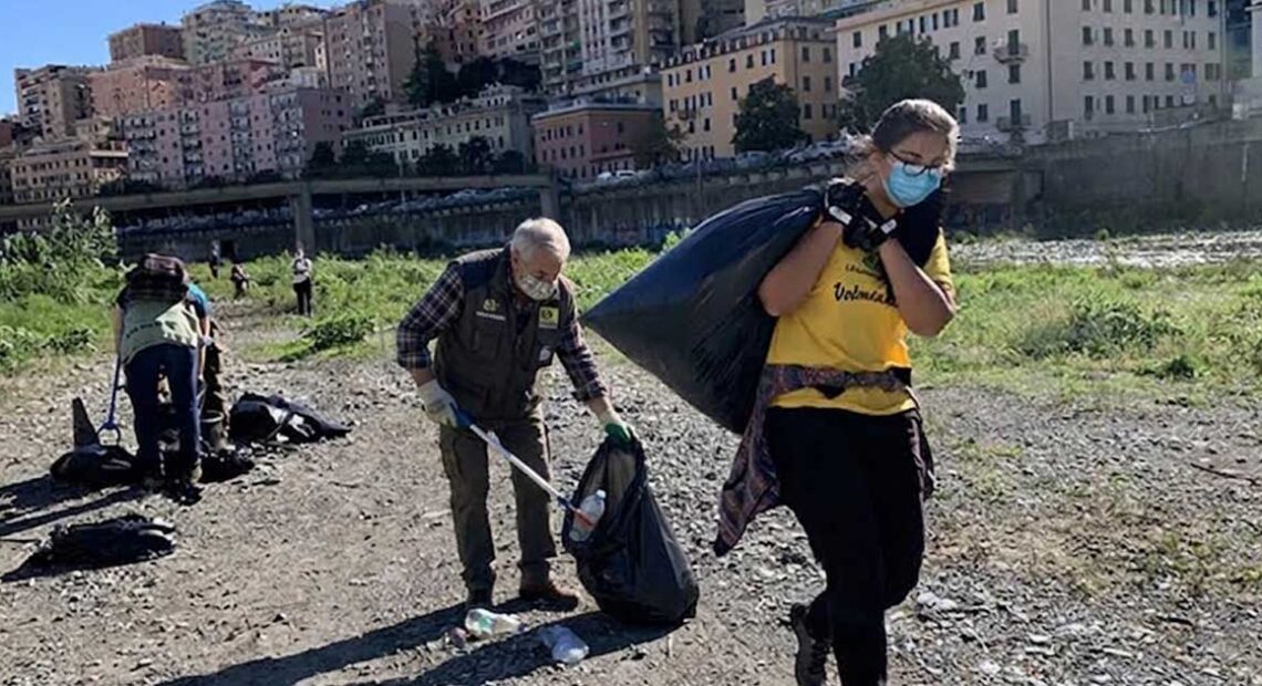 Volontari con guanti e sacchi neri impegnati nella raccolta rifiuti sulla spiaggia a Genova