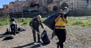 Volontari con guanti e sacchi neri impegnati nella raccolta rifiuti sulla spiaggia a Genova