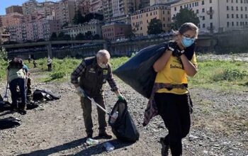 Volontari con guanti e sacchi neri impegnati nella raccolta rifiuti sulla spiaggia a Genova