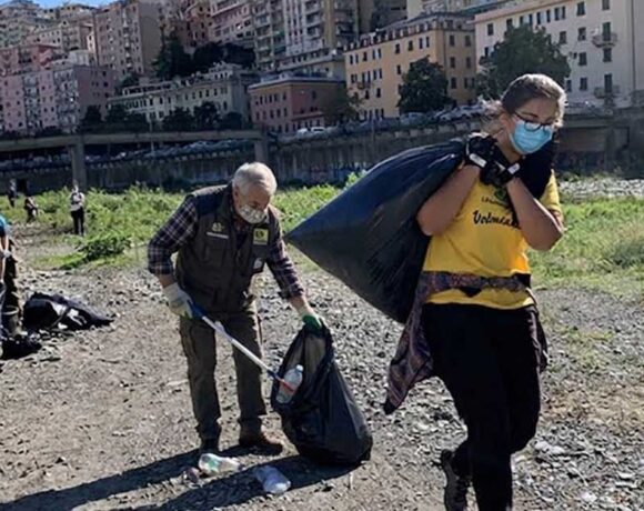 Volontari con guanti e sacchi neri impegnati nella raccolta rifiuti sulla spiaggia a Genova