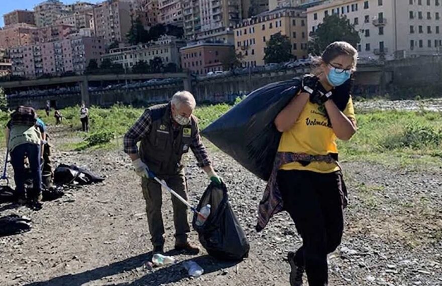Volontari con guanti e sacchi neri impegnati nella raccolta rifiuti sulla spiaggia a Genova