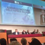 Assemblea Nazionale delle Imprese Balneari della fiera InOut a Rimini, con un grande schermo che proietta l'intervento e il titolo del dibattito sulle concessioni e il bando-tipo.