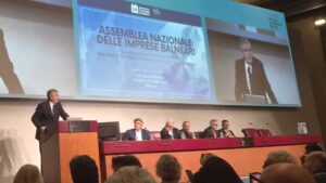 Assemblea Nazionale delle Imprese Balneari della fiera InOut a Rimini, con un grande schermo che proietta l'intervento e il titolo del dibattito sulle concessioni e il bando-tipo.