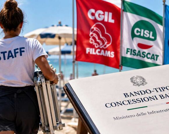 Lavoratrice in spiaggia con le bandiere dei sindacati Filcams, Fisascat e Uiltucs per il bando-tipo balneari