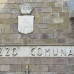 Facciata in pietra del Palazzo Comunale di Follonica con lo stemma del Comune.