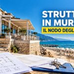 Progetto architettonico con chiavi in primo piano e struttura in muratura sul mare di uno stabilimento balneare pertinenziale