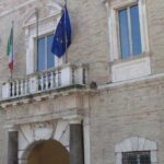 La facciata di Palazzo dei Priori, sede del Comune di Fermo, con le bandiere istituzionali