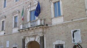 La facciata di Palazzo dei Priori, sede del Comune di Fermo, con le bandiere istituzionali