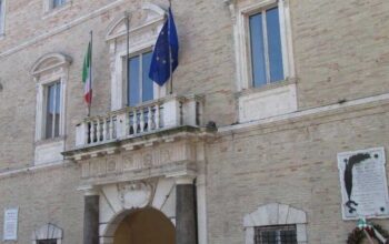 La facciata di Palazzo dei Priori, sede del Comune di Fermo, con le bandiere istituzionali