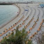 Vista dall'alto di una spiaggia attrezzata con ombrelloni ad Ancona sotto la falesia del Conero