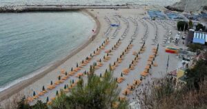 Vista dall'alto di una spiaggia attrezzata con ombrelloni ad Ancona sotto la falesia del Conero