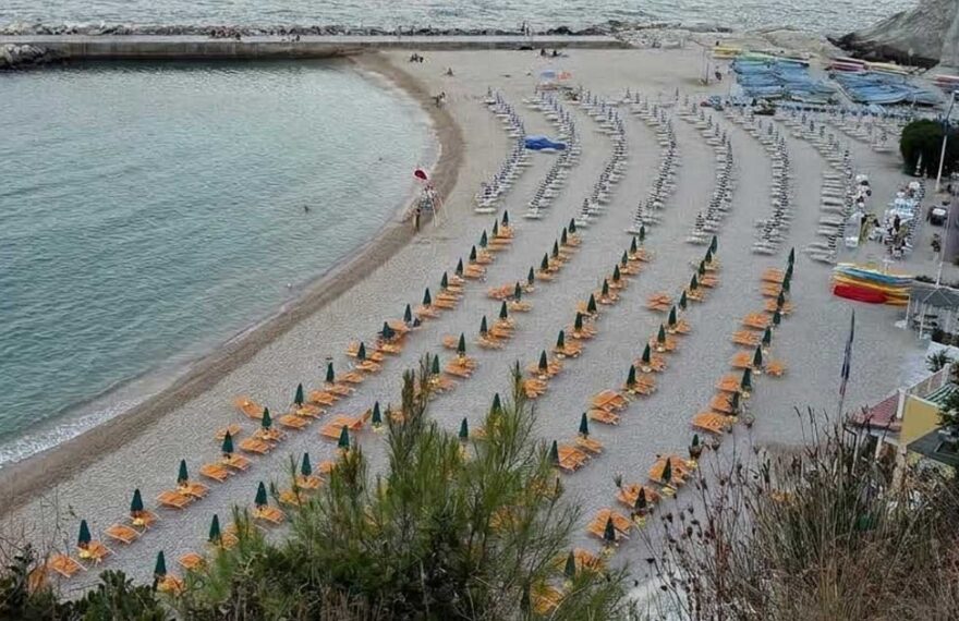 Vista dall'alto di una spiaggia attrezzata con ombrelloni ad Ancona sotto la falesia del Conero