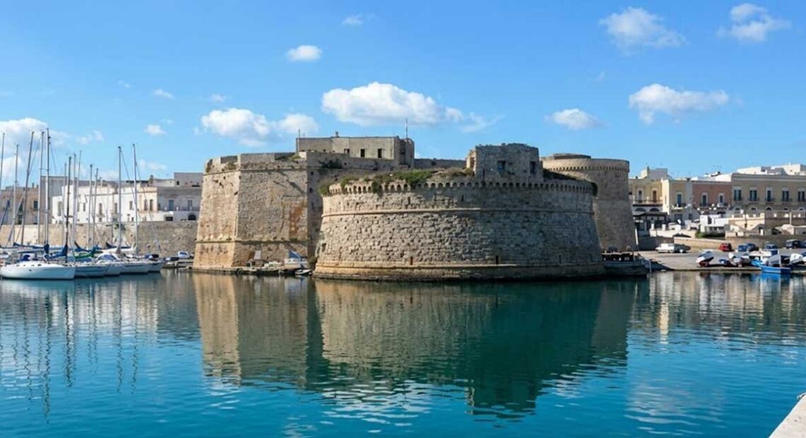 Vista del Castello Aragonese e del porto di Gallipoli riflessi sul mare azzurro