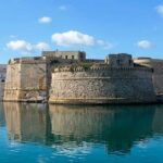 Vista del Castello Aragonese e del porto di Gallipoli riflessi sul mare azzurro