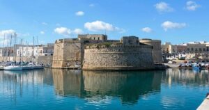 Vista del Castello Aragonese e del porto di Gallipoli riflessi sul mare azzurro