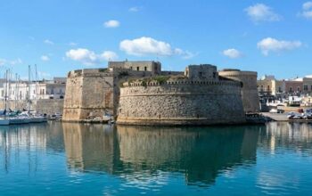 Vista del Castello Aragonese e del porto di Gallipoli riflessi sul mare azzurro