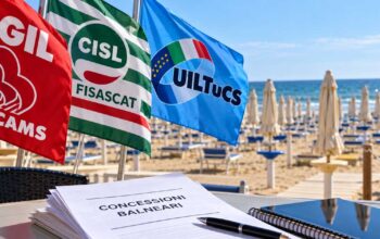 Bandiere sindacali di Filcams Cgil, Fisascat Cisl e Uiltucs in spiaggia con documento su gare balneari Comacchio.