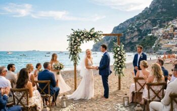 Cerimonia di matrimonio in spiaggia sulla sabbia con arco floreale e invitati al mare