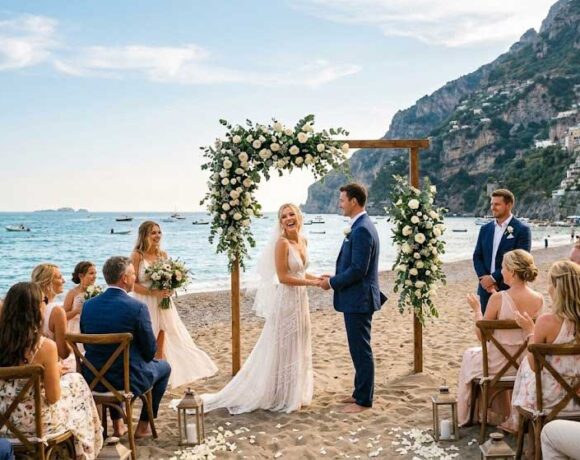 Cerimonia di matrimonio in spiaggia sulla sabbia con arco floreale e invitati al mare