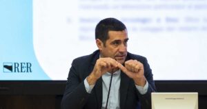 Il presidente della Regione Emilia-Romagna Michele De Pascale durante un intervento pubblico con il logo RER sullo sfondo