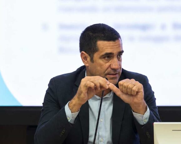 Il presidente della Regione Emilia-Romagna Michele De Pascale durante un intervento pubblico con il logo RER sullo sfondo