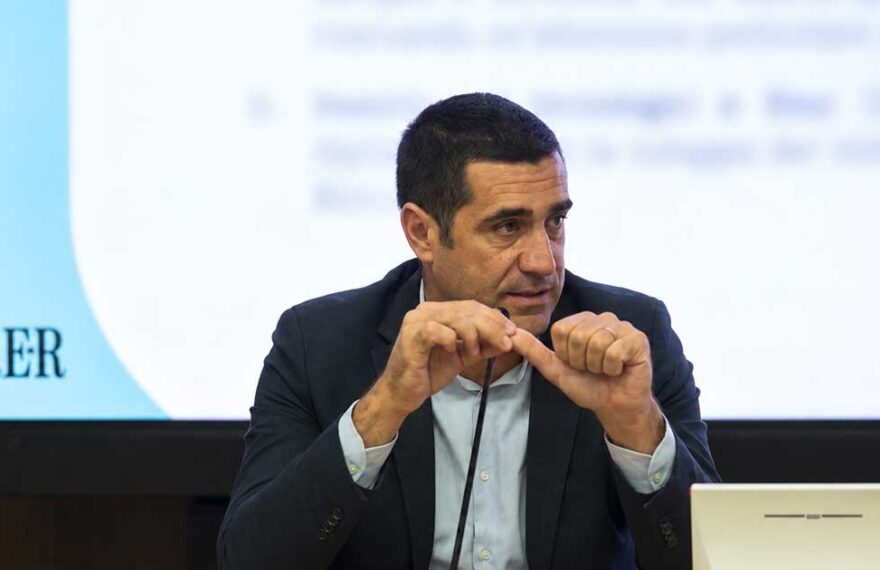 Il presidente della Regione Emilia-Romagna Michele De Pascale durante un intervento pubblico con il logo RER sullo sfondo