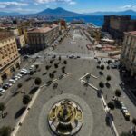Veduta dall'alto di Piazza Municipio a Napoli con Castel Nuovo e il Vesuvio sullo sfondo