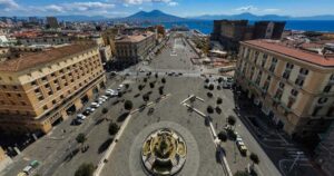 Veduta dall'alto di Piazza Municipio a Napoli con Castel Nuovo e il Vesuvio sullo sfondo