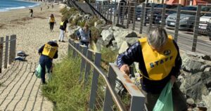 Volontari in gilet giallo impegnati nella pulizia dei rifiuti lungo la passeggiata e la spiaggia di Savona.