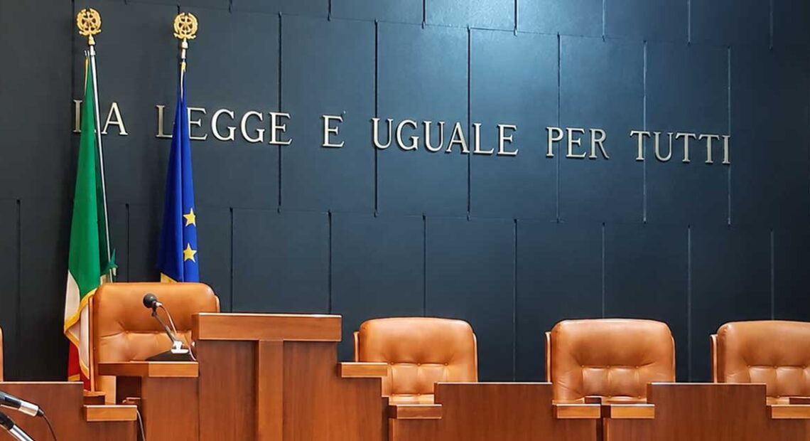 Aula di tribunale italiana vuota con il banco dei giudici e la scritta La legge è uguale per tutti