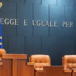 Aula di tribunale italiana vuota con il banco dei giudici e la scritta La legge è uguale per tutti