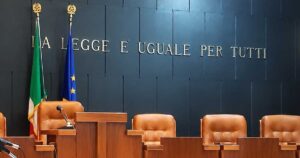 Aula di tribunale italiana vuota con il banco dei giudici e la scritta La legge è uguale per tutti