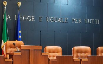 Aula di tribunale italiana vuota con il banco dei giudici e la scritta La legge è uguale per tutti
