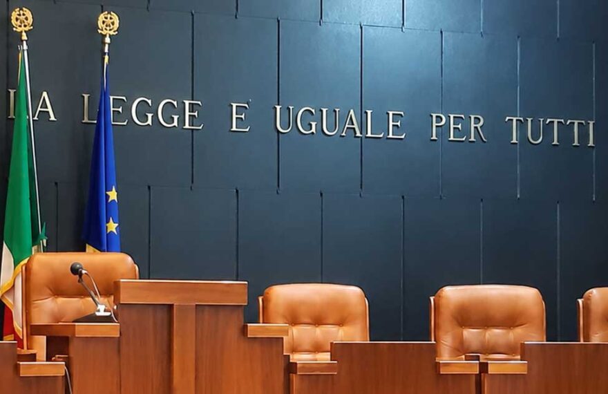 Aula di tribunale italiana vuota con il banco dei giudici e la scritta La legge è uguale per tutti