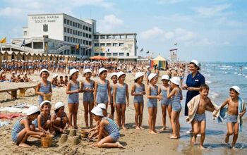 Bambini in costume da bagno giocano sulla spiaggia davanti all'edificio della colonia marina Sole e Mare